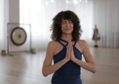 Yoga teacher doing salutation seal in inside yoga studio