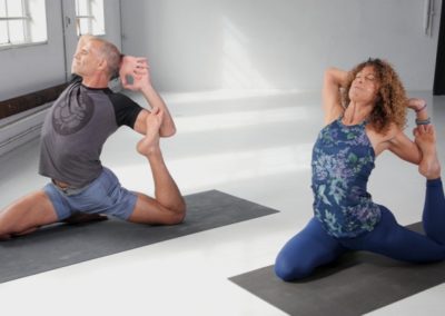 yoga teachers doing king pigeon yoga asana in bright yoga studio