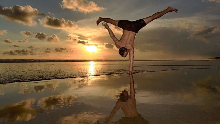 Young Ho Kim doing a one-arm balance at beach