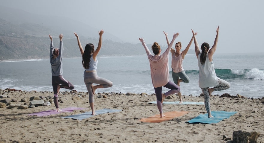 Gruppe, die am Strand Yoga praktiziert